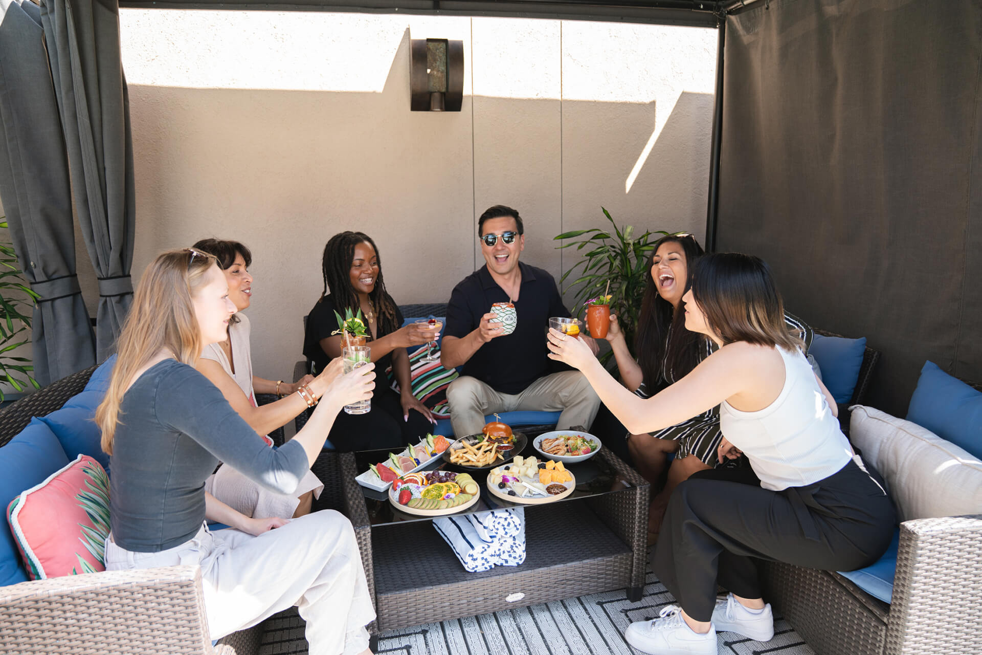 A group of friends enjoying a lively gathering, sharing drinks and food under a canopy in Santa Clara, California.