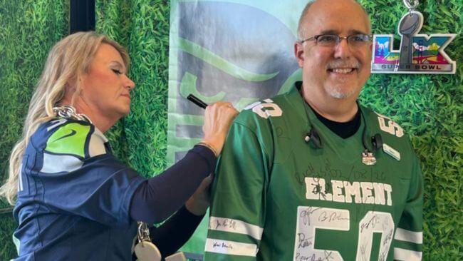 What It Really Takes to Host the Super Bowl in Santa Clara 2026 A woman signs a jersey for a man at an NFL Super Bowl event in Santa Clara, California.