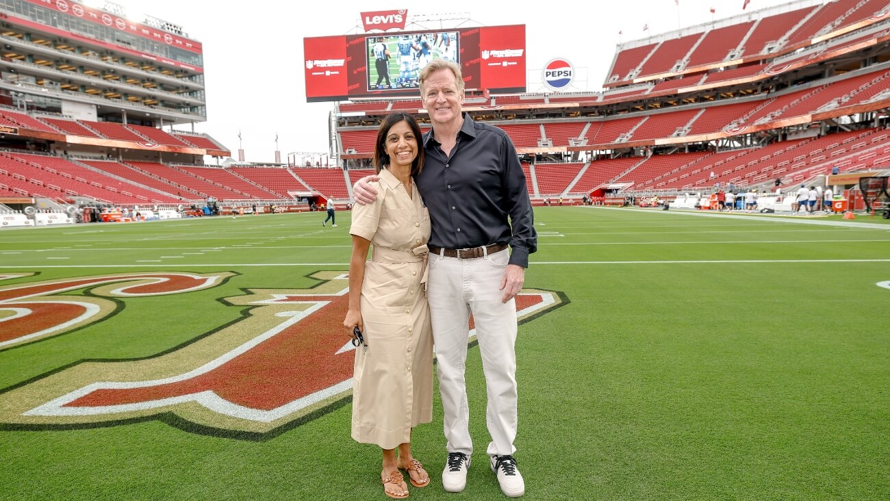A couple poses on a football field at a stadium, smiling at the camera in Santa Clara, California.