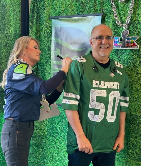A woman signs a Seattle Seahawks jersey while a man poses for a photo in Santa Clara, California.