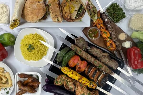 Fatima Bazaar & Cairo Grill A variety of grilled skewers, including meat, vegetables, and seafood, accompanied by sides like yellow rice and dips in Santa Clara, California.