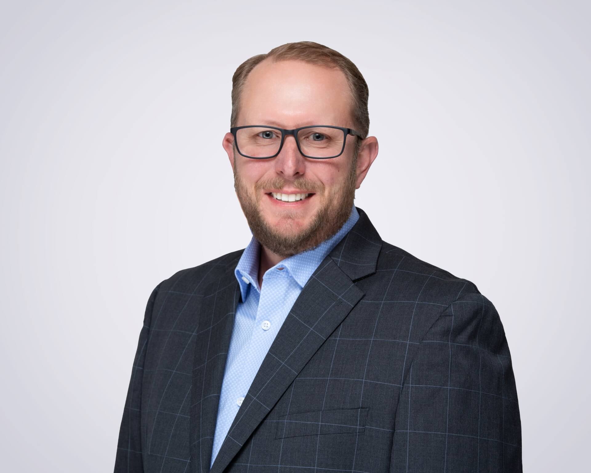 Dịch vụ đích đến A man with glasses and a beard wearing a blue checkered shirt and a dark gray suit jacket smiles at the camera in Santa Clara, California.