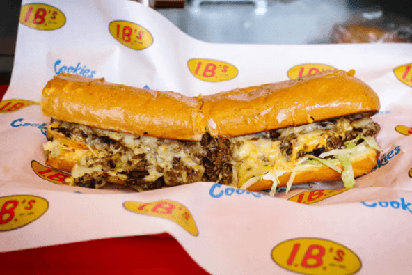 A large, toasted sandwich with melted cheese and meat, served on a red tray in Santa Clara, California.