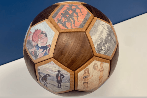 A wooden ball with hexagonal panels featuring various historical and cultural scenes in Santa Clara, California.