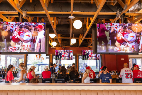 Clara's Junction Levi's® Stadium Match Day Watch Party (Qatar vs Switzerland) A lively sports bar filled with patrons watching multiple TV screens showing football games in Santa Clara, California.