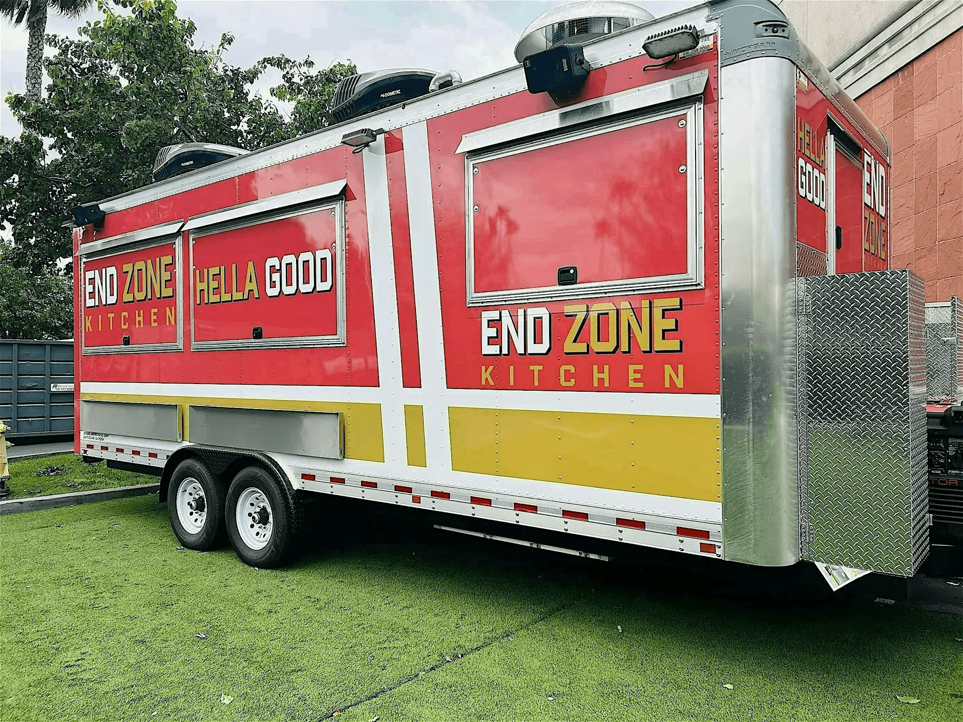 A vibrant red and yellow food truck named 'End Zone Kitchen' parked on a grassy area, ready to serve delicious meals in Santa Clara, California.