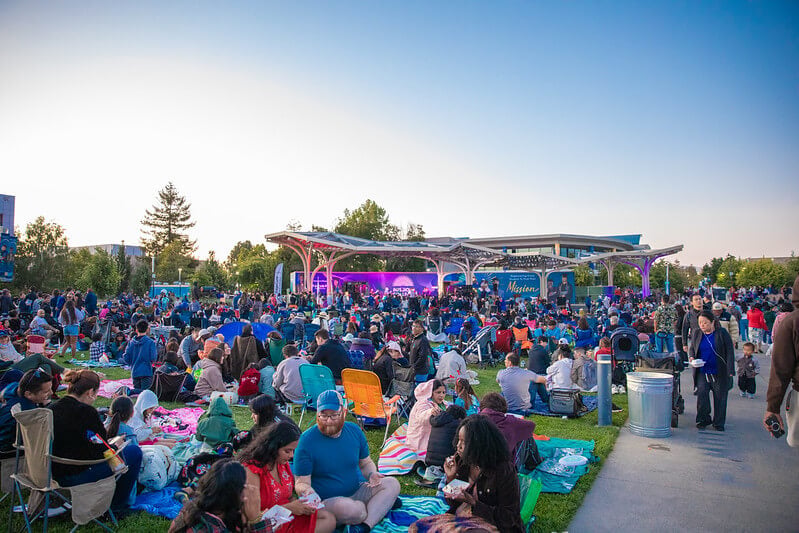 City of Santa Clara Fourth of July Community Celebration A vibrant outdoor concert with a large crowd enjoying music under a colorful stage canopy in Santa Clara, California.