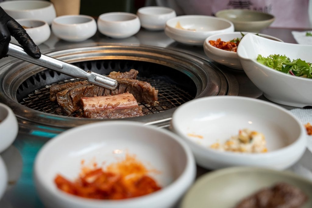 Kyopo BBQ A gloved hand uses tongs to grill beef ribs on a Korean barbecue grill in Santa Clara, California.