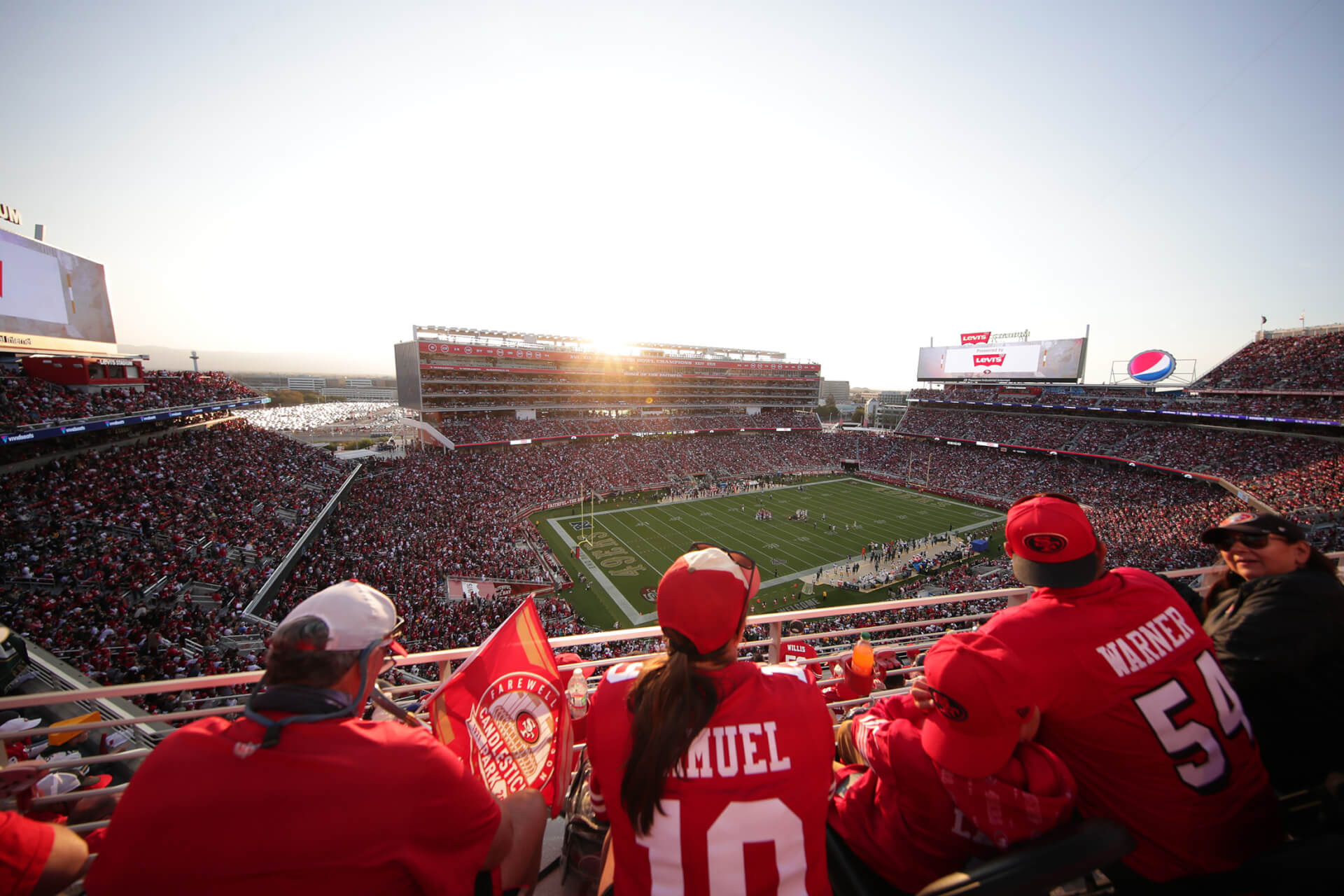 Your Gameday Guide to Santa Clara Fans in red jerseys watch a football game at a large stadium during sunset in Santa Clara, California.