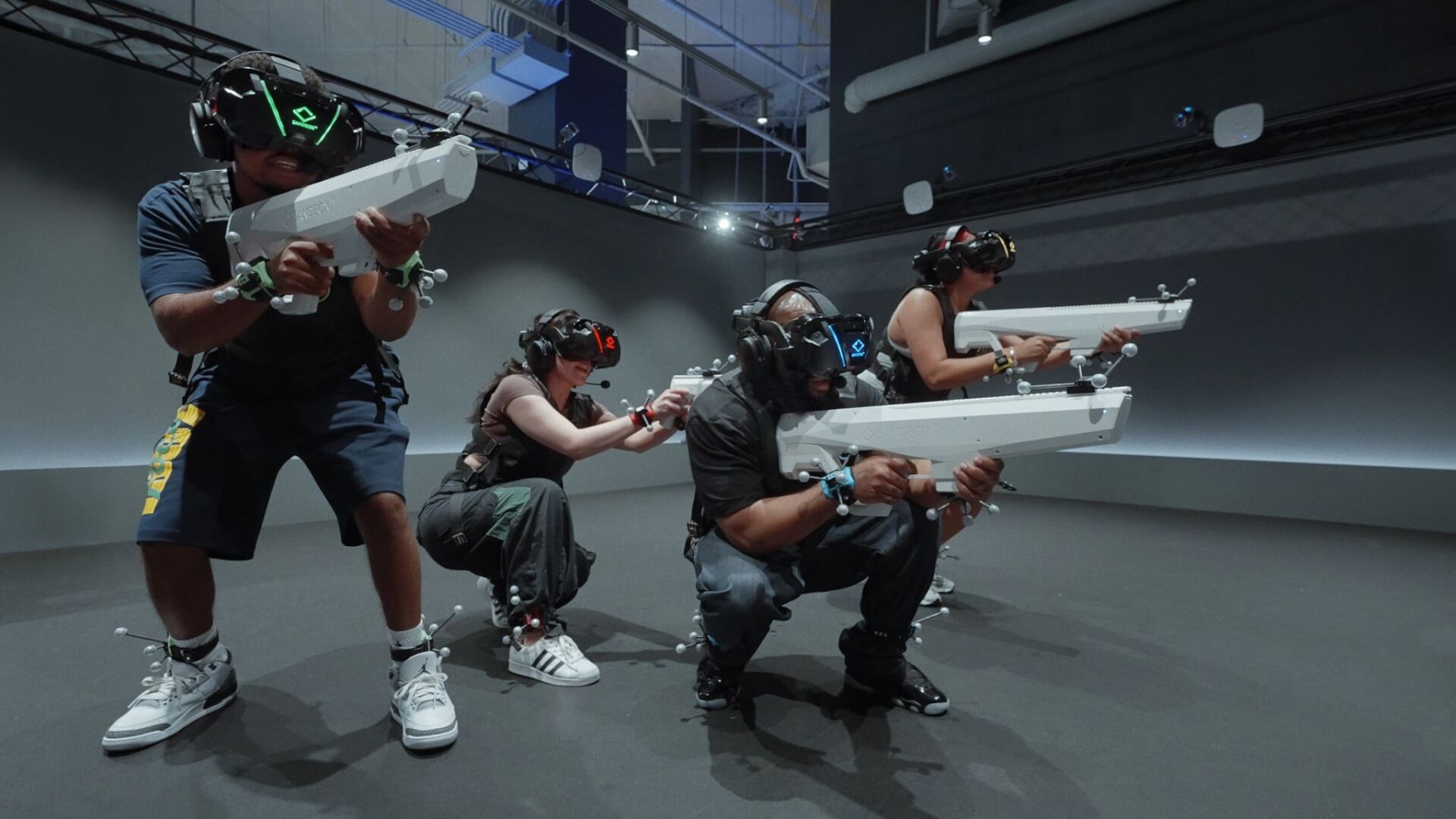 Sandbox VR at Westfield Valley Fair People wearing VR headsets and holding prop guns in a motion capture studio in Santa Clara, California.