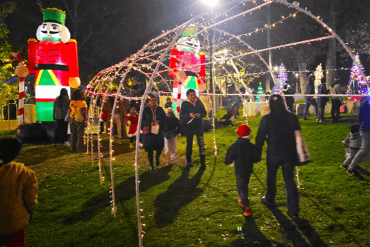 Santa Clara Holiday Tree Lighting 2026 People walking through a festive light tunnel with giant inflatable nutcrackers at night in Santa Clara, California.
