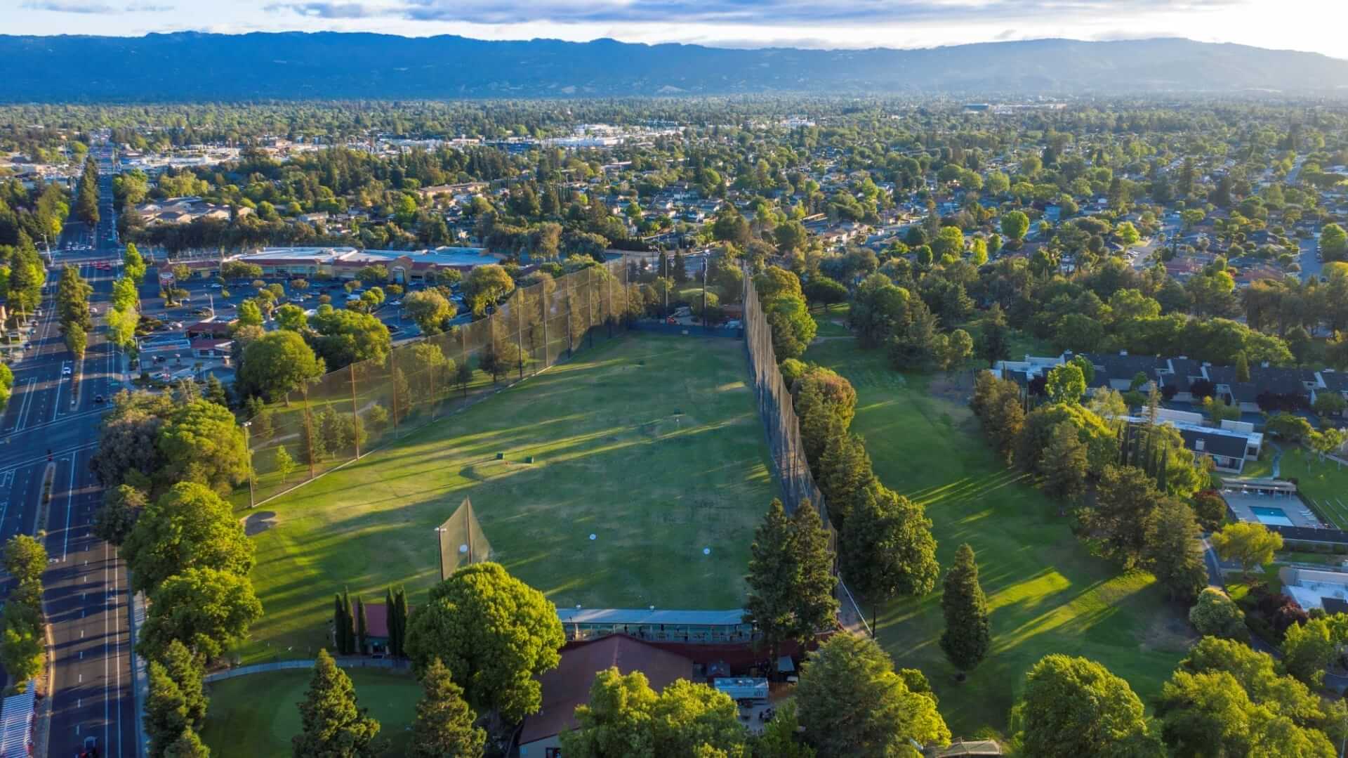 An aerial view of a driving range surrounded by trees and a suburban neighborhood in Santa Clara, California.