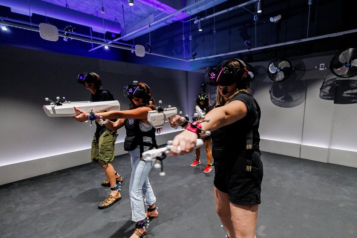People wearing VR headsets and vests holding motion-tracked controllers in a gaming arena in Santa Clara, California.