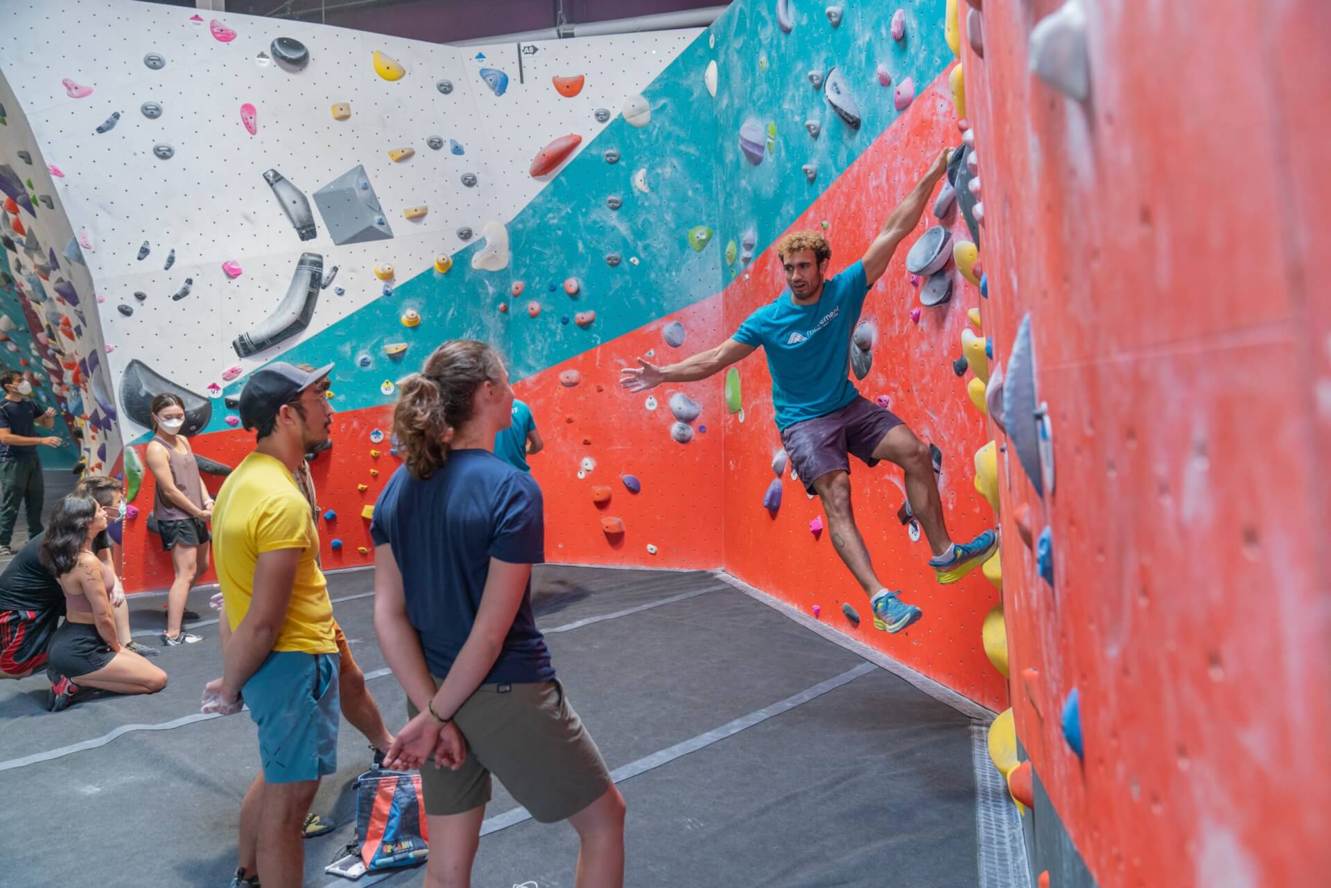 A man demonstrates a climbing move on a wall for a group of observers in Santa Clara, California.