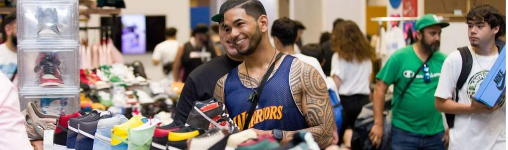 November Events in Santa Clara 2026 A smiling man with tattoos browsing a large collection of sneakers at a convention in Santa Clara, California.