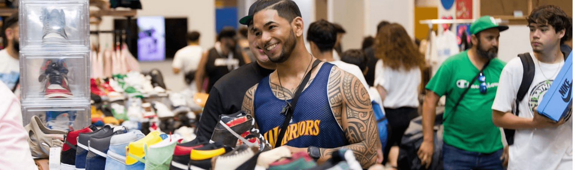 November Events in Santa Clara 2026 A smiling man with tattoos browsing a large collection of sneakers at a convention in Santa Clara, California.