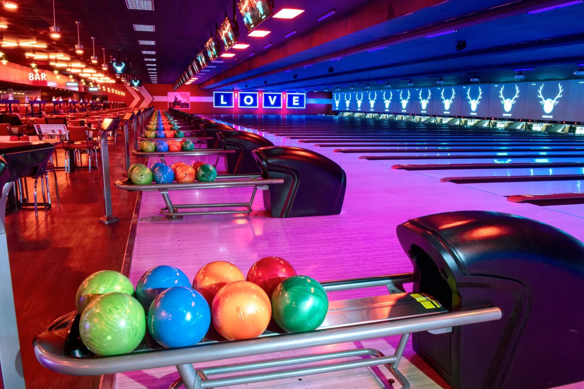 A bowling alley with colorful balls on racks and neon lighting in Santa Clara, California.